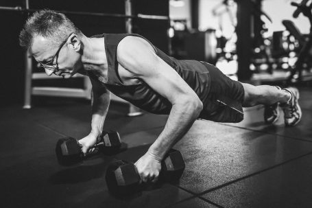 Mann macht Liegestütze mit Hanteln im Fitnessstudio.