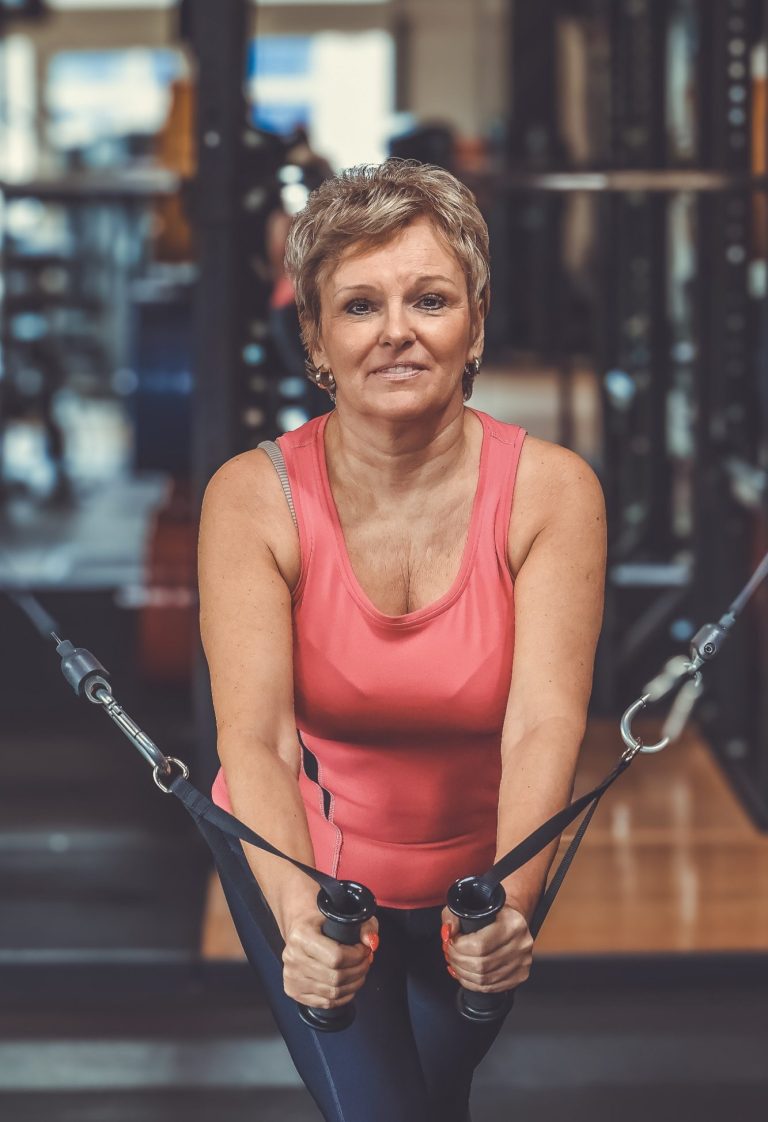 businesshooting krefeld Eine sportliche Frau in einem Fitnessstudio zieht mit beiden Händen Widerstandsbänder.