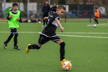 Ein Junge schießt einen Fußball auf einem Kunstrasenplatz.