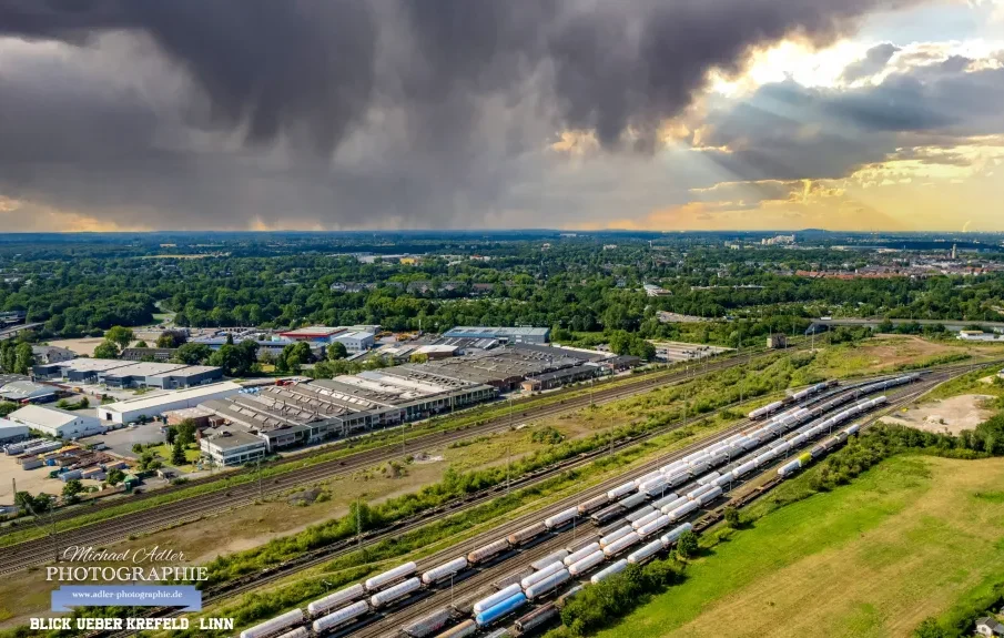 Professionelle Drohnen Fotografie bei Adler Photographie Krefeld Blick auf eine verregnete Landschaft mit Zügen und einer dichten Wolkendecke.