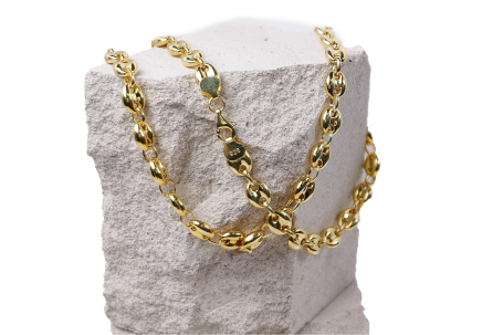 Goldene Kette auf einem weißen Stein, geschmackvoll drapiert.