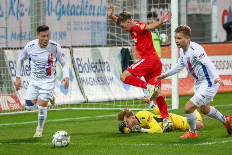 Aktion während eines Fußballspiels, Spieler springt über einen Torwart und Gegner.