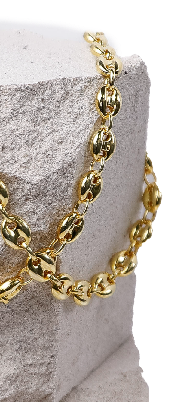 produktfotografie in krefeld businessfotograf adler photographie fotostudio Goldene Kette mit ovalen Gliedern, drapiert über einem weißen Untergrund.
