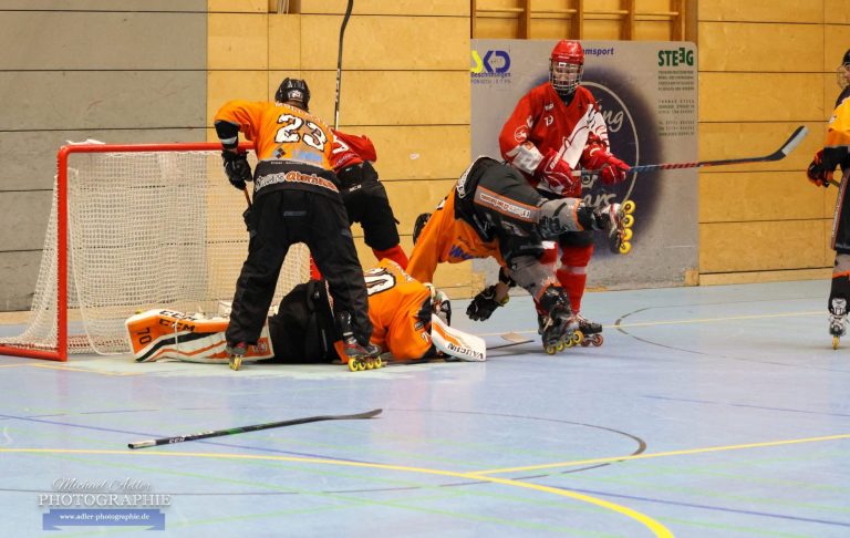 Eventfotografie Krefeld Zwei Spieler kämpfen um den Puck vor dem Tor, ein Torwart ist am Boden.