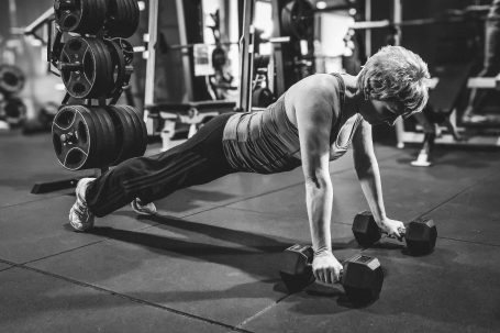 Person macht Liegestütze mit Kurzhanteln in einem Fitnessstudio.