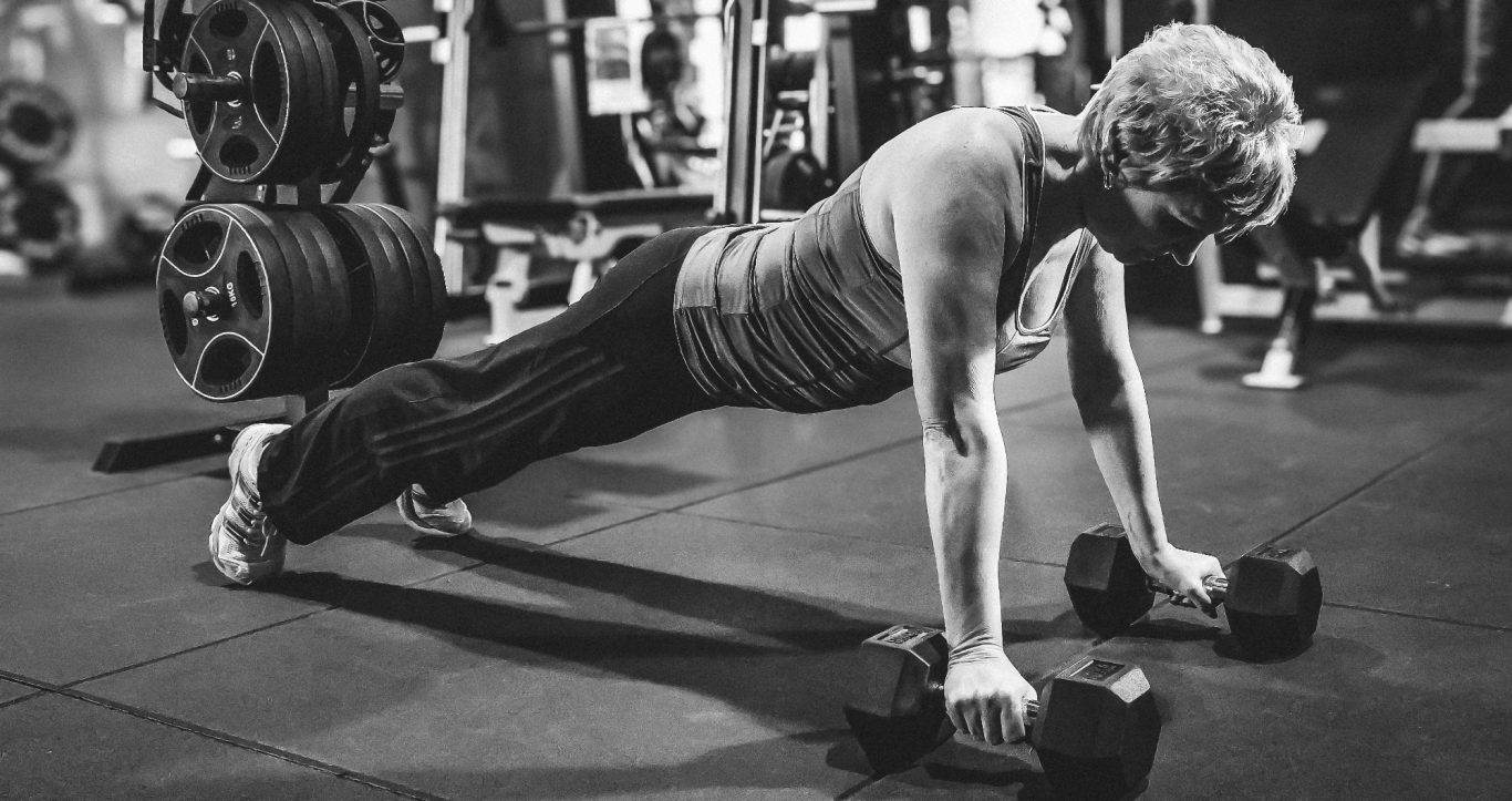 businessshooting adler photographie Person macht Liegestütze mit Hanteln im Fitnessstudio. Schwarzweißaufnahme.