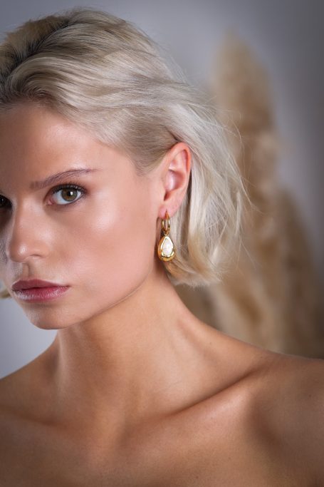 Porträt einer Frau mit blonden Haaren und schimmernden Ohrringen.