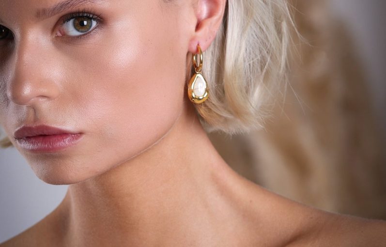 produktfotografie in krefeld businessfotograf adler photographie fotostudio Porträt einer Frau mit blonden Haaren, die elegante goldene Ohrringe trägt.