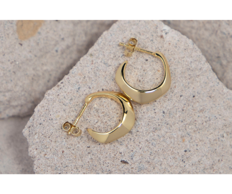 Goldene Ohrringe mit rundem, poliertem Design auf sandfarbenem Hintergrund.