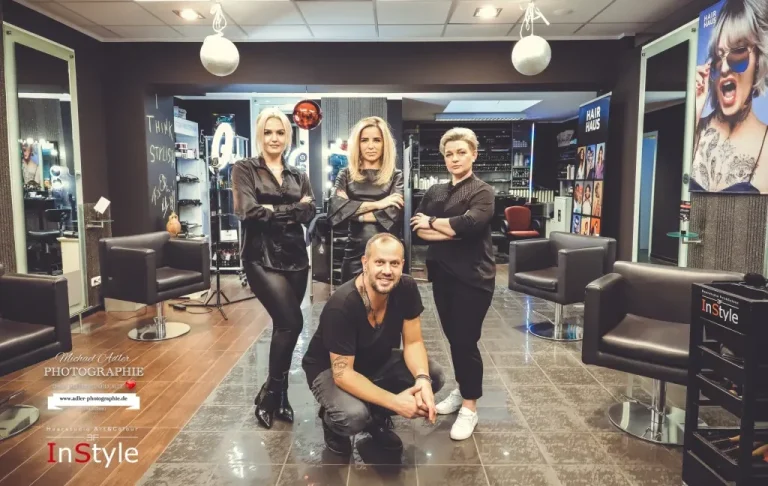 Vier Personen in einem Friseursalon, zwei Frauen stehen, ein Mann und eine Frau sitzen.