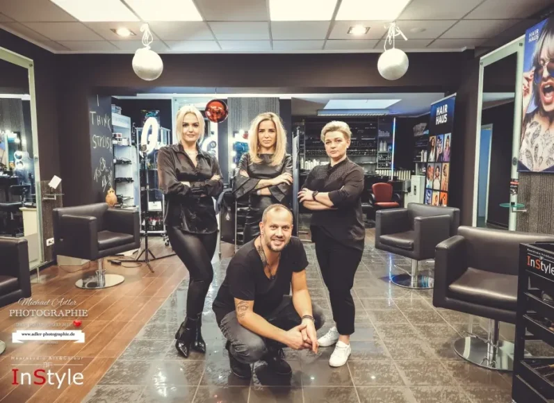 Adler Photographie Krefeld Fünf Friseure posieren in einem modernen Salon. Friseur- und Stylingumgebung sichtbar.