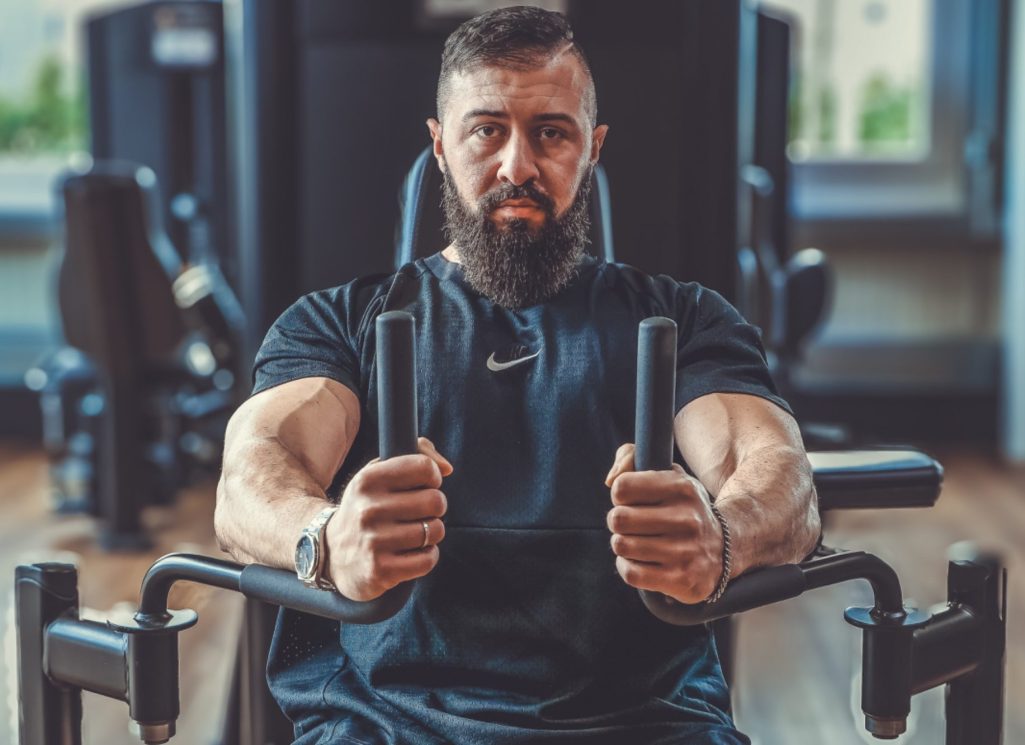 Businessshooting Krefeld Adler Photographie Mann mit Bart trainiert an Fitnessgerät im Fitnessstudio.