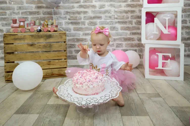 Kleines Kind in Tutu mit einer Torte auf einem Tablett in einem bunten Raum.