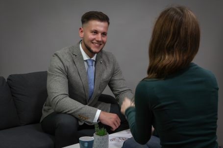 Ein Mann und eine Frau schütteln sich die Hände in einem formellen Gespräch.