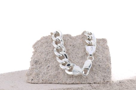 Silberner Armband auf einer sandfarbenen Oberfläche.
