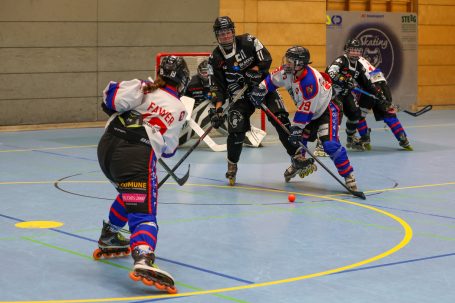 Spielszene eines Rollhockey-Spiels mit Spielern in actionreichen Positionen.