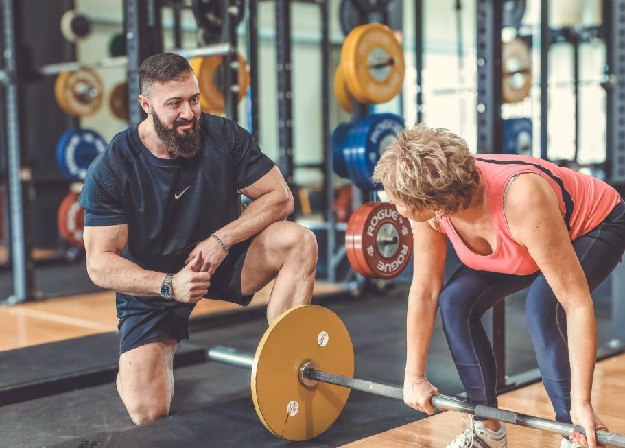 Businesshooting krefeld Ein Trainer hilft einer Frau beim Gewichtheben im Fitnessstudio.