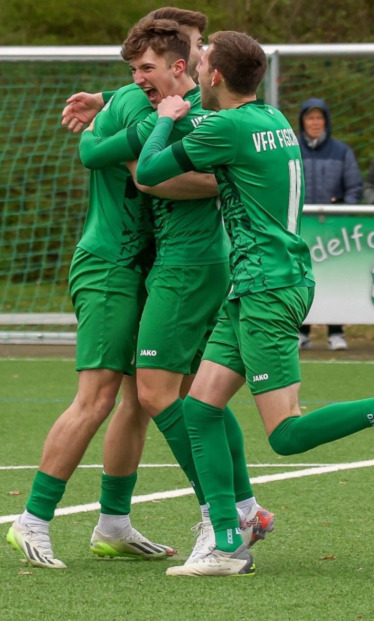 Adler Photographie Eventfotografie Drei jubelnde Fußballspieler in grüner Ausrüstung umarmen sich auf dem Spielfeld.