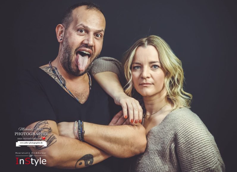 Adler Photographie krefeld Fotograf Mann zeigt Zunge, Frau steht lächelnd neben ihm, beide posieren professionell.