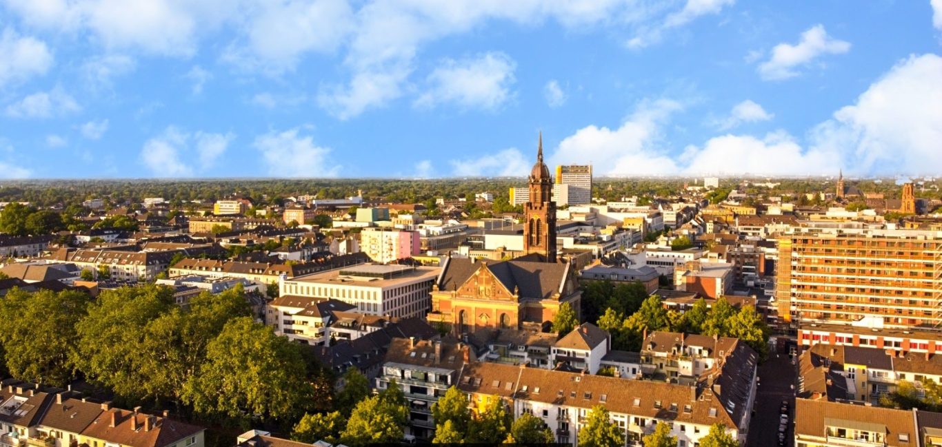 Professionelle Drohnen Fotografie bei Adler Photographie Krefeld Blick auf eine Stadt mit historischen Gebäuden und grünen Bäumen im Vordergrund.
